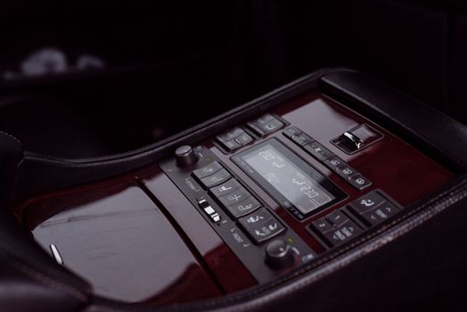 Close-up of luxury car control console displaying modern electronics and sleek design.