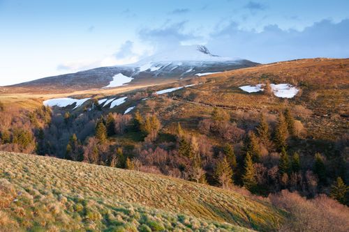 Free Stunning landscape of Mont-Dore, Auvergne with rolling hills and snow patches in late spring. Stock Photo