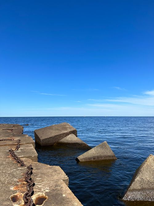 Free Serene view of the ocean and sky with concrete blocks on a sunny day. Stock Photo
