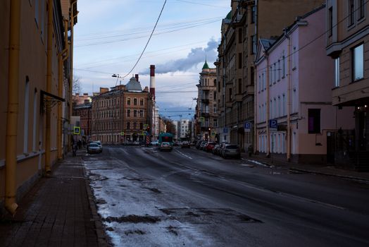 A moody winter street scene featuring historical buildings and wet asphalt in a traditional urban setting.