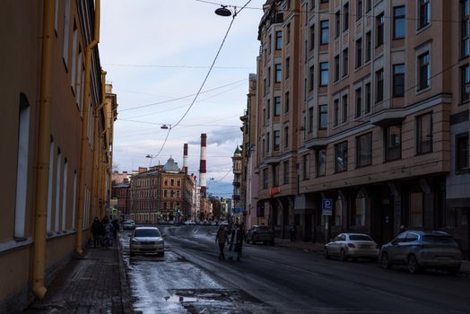 City street view with cars and pedestrians flanked by urban architecture.