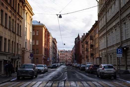 An urban street lined with cars and traditional architecture in winter.
