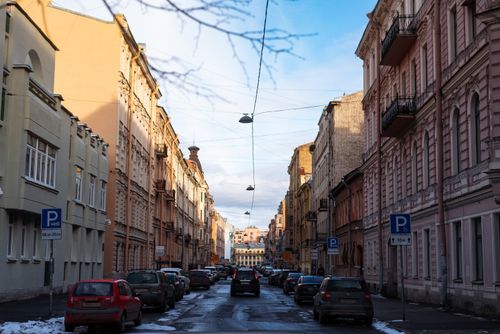 Free A picturesque urban street with cars, historical buildings, and light snow, captured in winter. Stock Photo
