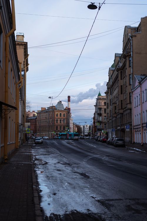 Free Empty city street lined with historic buildings and puddles, reflecting overcast skies. Stock Photo