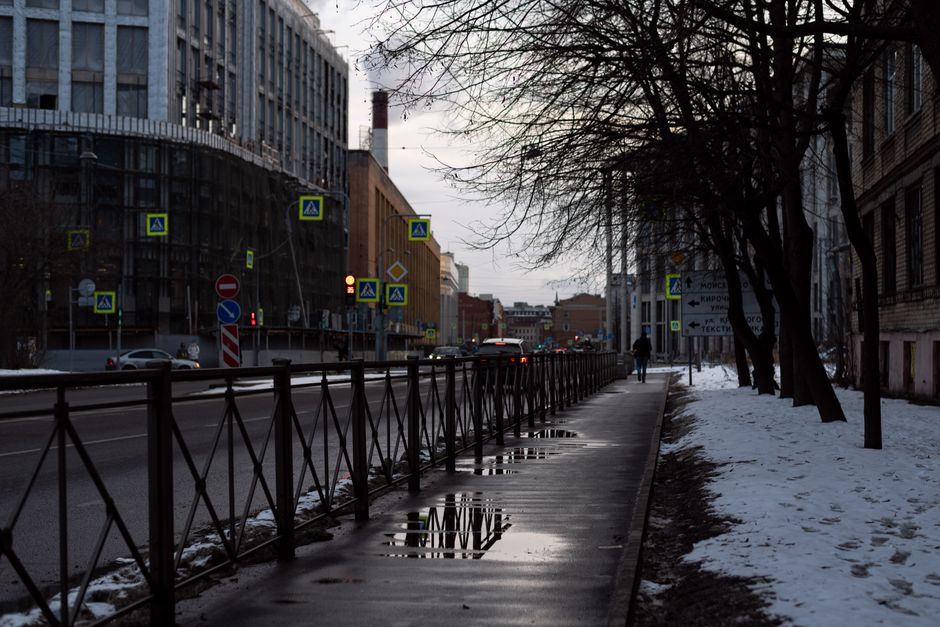 City street in winter with snow and reflections on wet sidewalk and street.