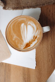 Top view of a coffee cup with beautiful latte art on a rustic wooden table setting.