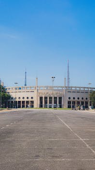 Wide view of Pacaembu Stadium with an empty parking lot under a clear blue sky, São Paulo, Brazil.