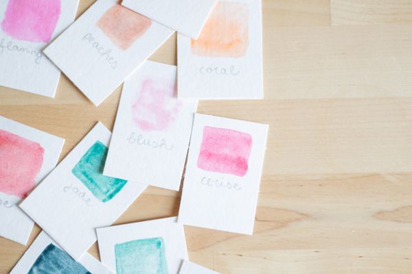 Painted colour swatch cards on a light wooden desk — photo by Fiona Murray on Pexels