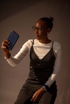 African woman taking a selfie with smartphone in a studio.