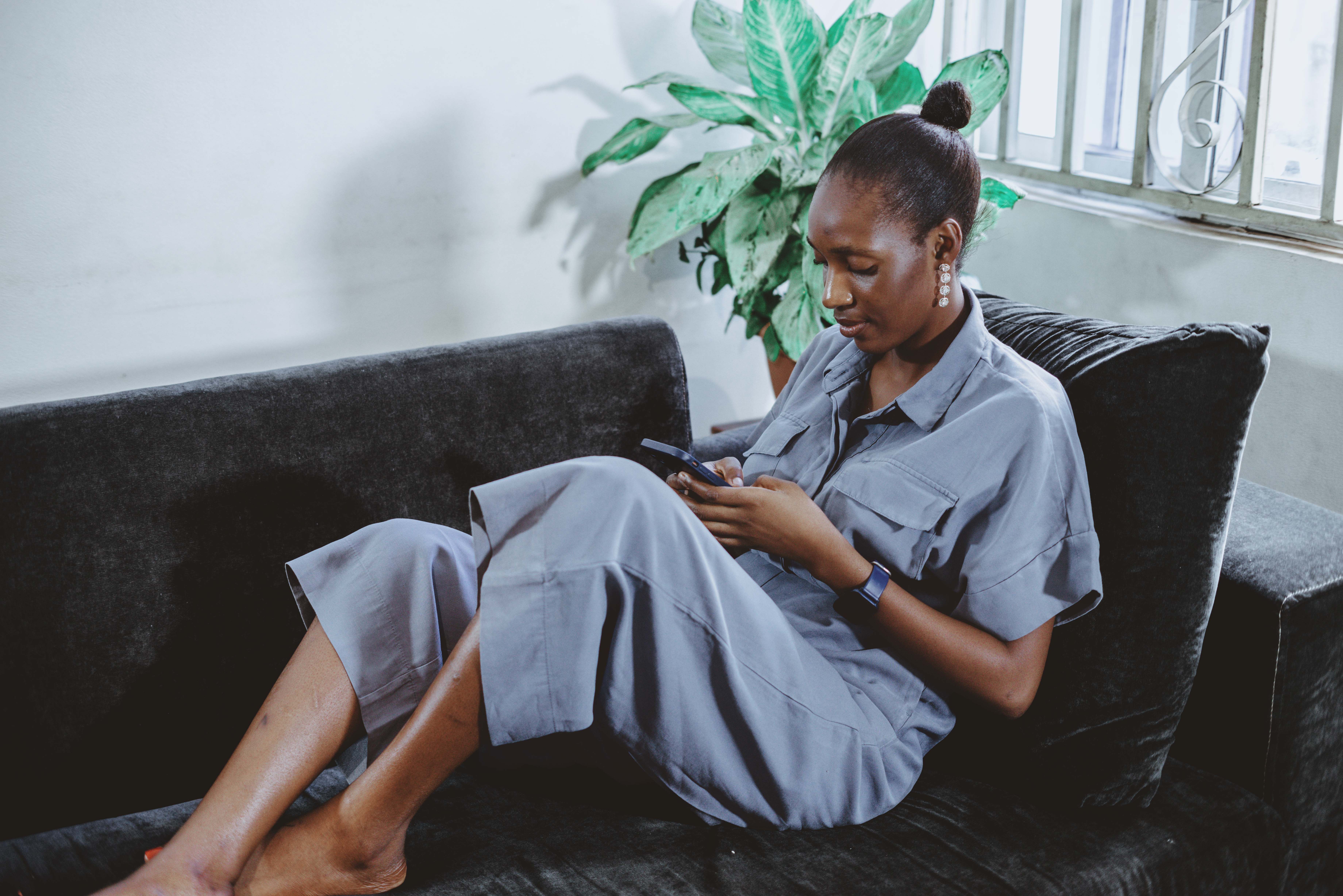 Illustrative image of an adult woman using a smartphone at home in Abuja, Nigeria