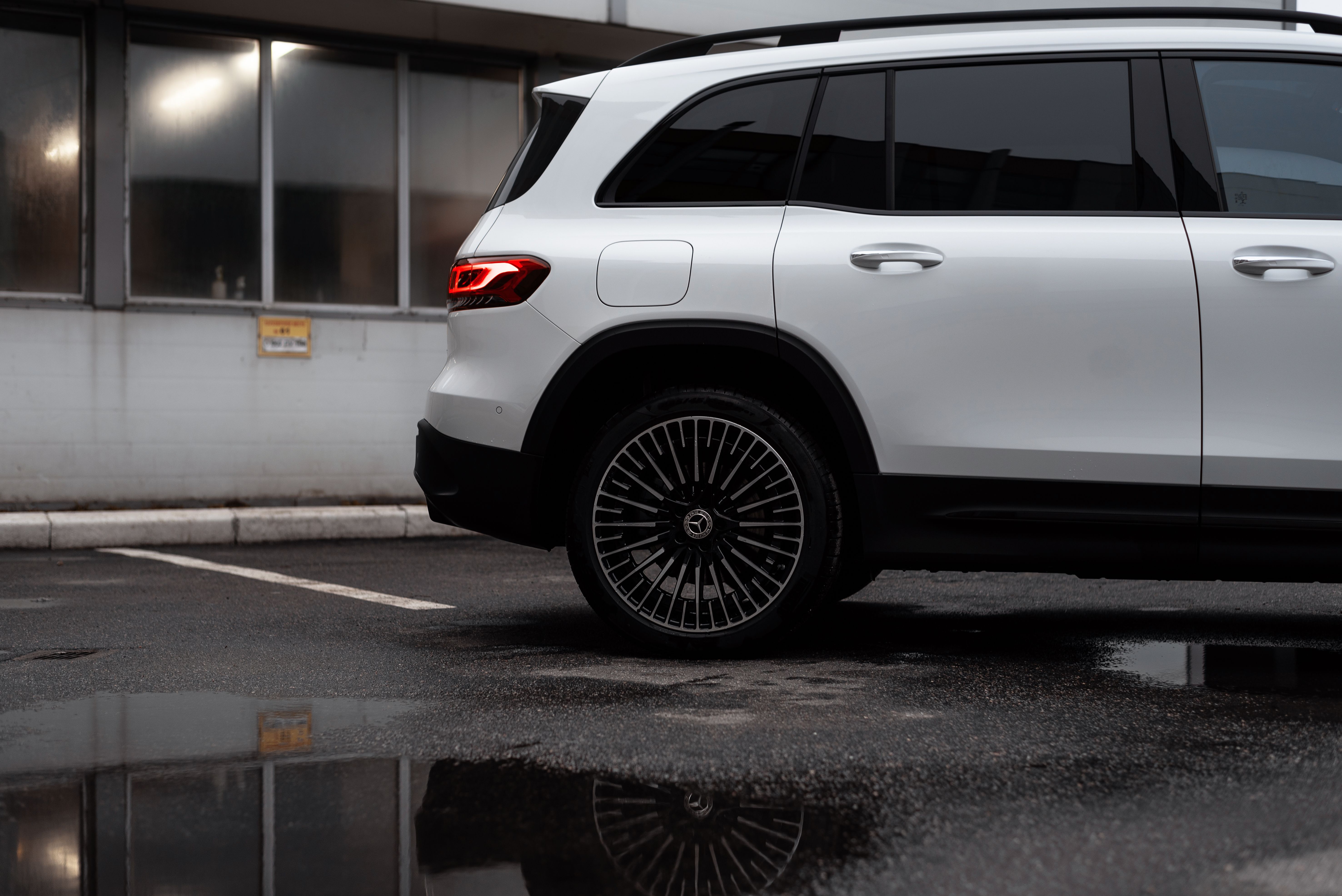 Mercedes-Benz EQB SUV parked in a city lot, reflected in a puddle.