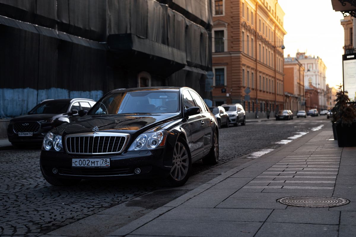 Black luxury sedan parked on a city street outside an upscale hotel entrance