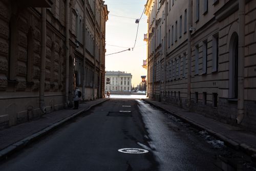 Free A narrow urban alleyway leading to a bright open area with historic architecture in winter. Stock Photo