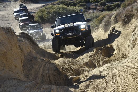 Convoy of Off-Road Cars Crossing a Rough Hilly Terrain