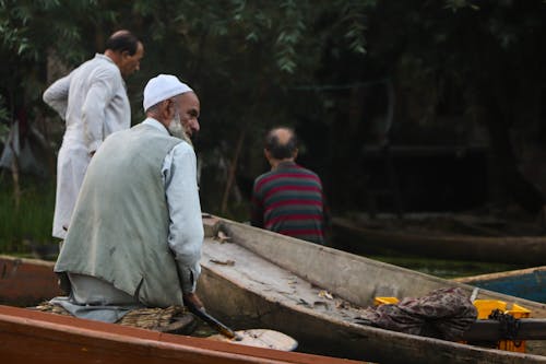 Elderly Man Sitting in a Boat on the Shore 