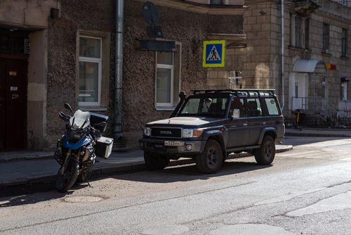 Free Parked SUV and motorcycle on a city street with a pedestrian crossing sign. Stock Photo