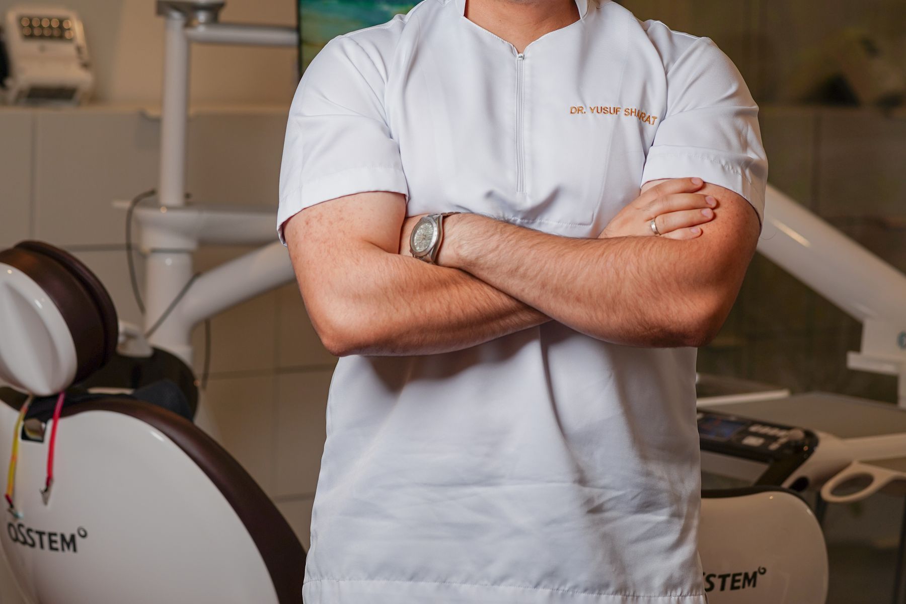 Smiling dental professional standing beside a treatment chair in a modern orthodontic practice