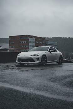 A sleek Toyota GT86 parked in a rainy cityscape captures urban elegance.