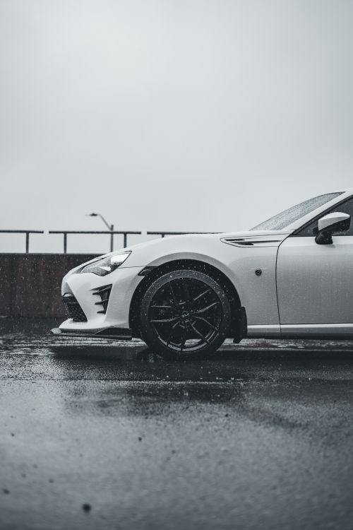 Free Close-up of a white sports car parked in wet urban environment with rain falling. Stock Photo