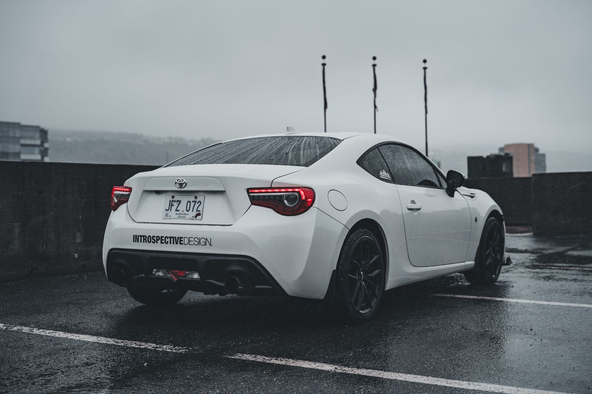A stylish white Toyota sports car parked in an urban setting on a rainy day.