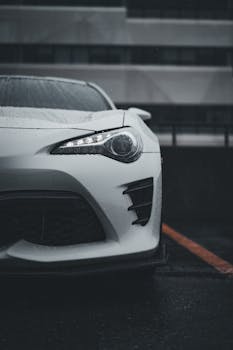 Elegant white sports car captured in urban setting on a rainy day.