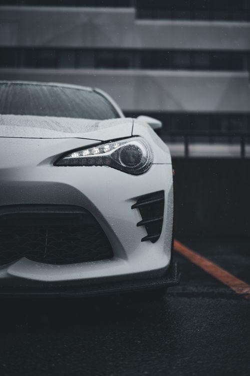 Free Elegant white sports car captured in urban setting on a rainy day. Stock Photo