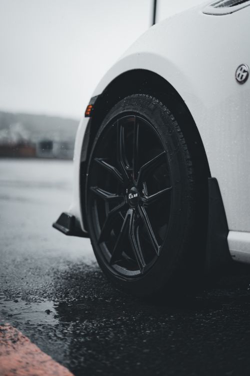 Free Close-up shot of a sports car wheel with raindrops on a wet road surface. Stock Photo