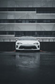 Modern white sports car parked in a dimly lit urban area, showcasing sleek design and elegance.