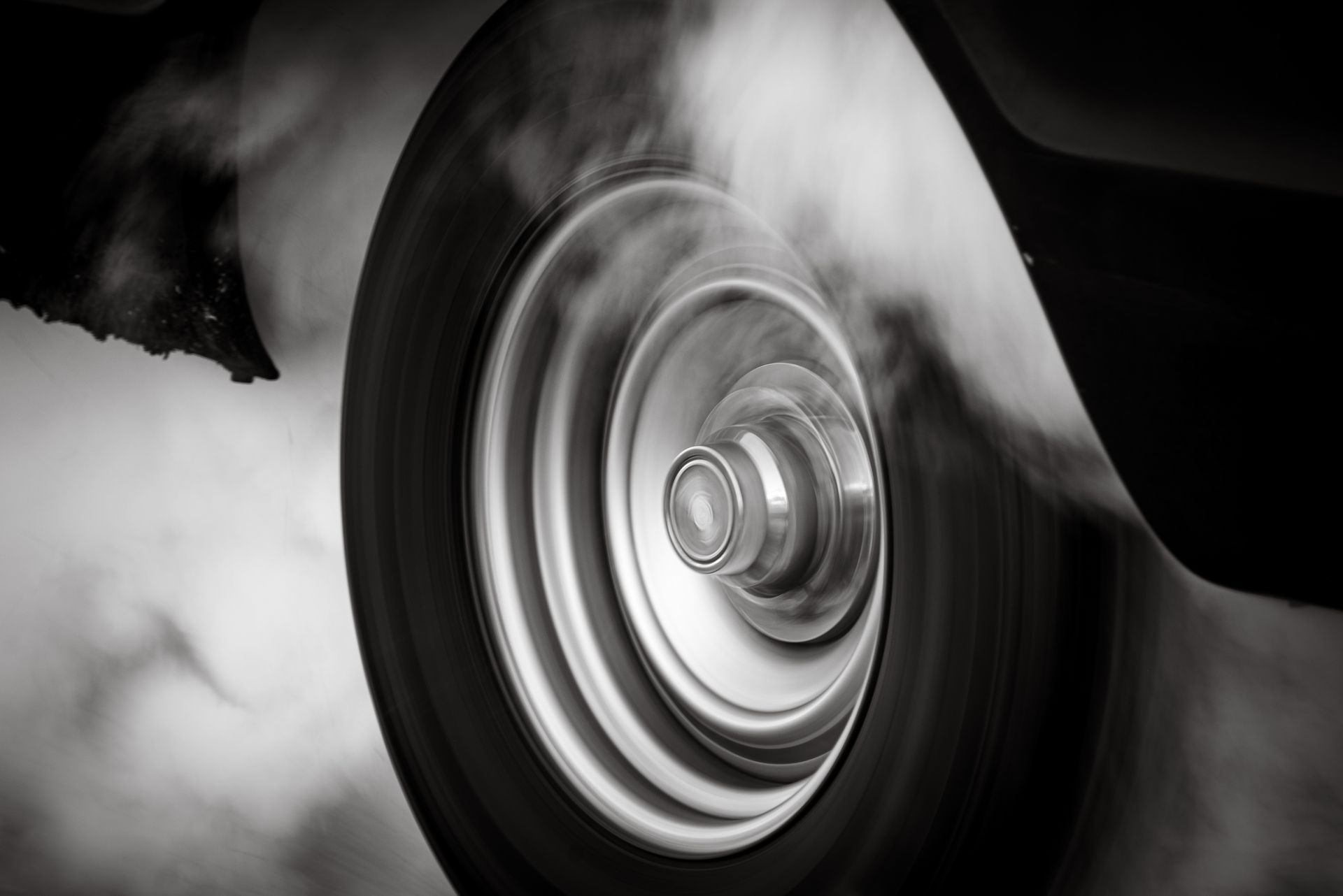 Dynamic close-up of a spinning car wheel emitting smoke, capturing motion and speed.