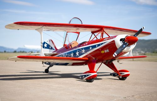 Free Colorful red and blue vintage biplane with star detailing parked on an airstrip under clear skies. Stock Photo