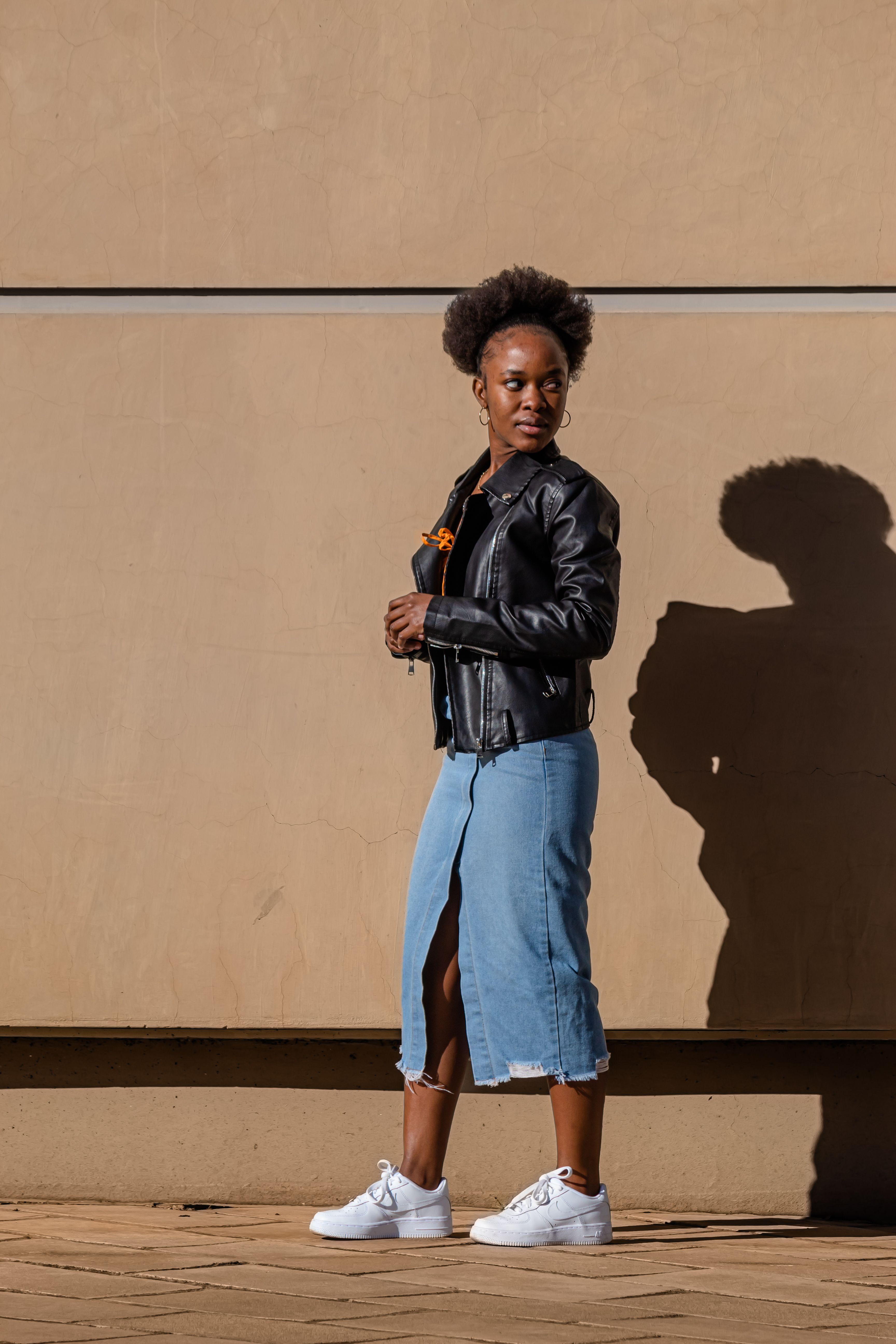 Woman in a black leather jacket with a blue denim midi skirt
