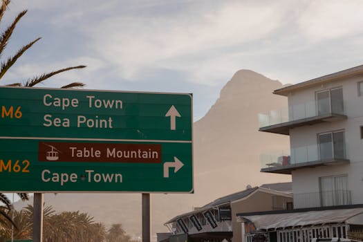 Road sign pointing to Cape Town and Table Mountain with the iconic peak in the background.