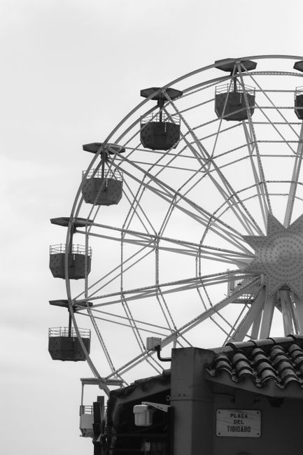 Captivating black and white photo of the iconic Ferris wheel at Tibidabo amusement park, Barcelona.