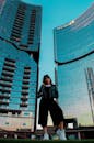 一位时尚女性在现代摩天大楼前，迎着明亮的天空摆出姿势