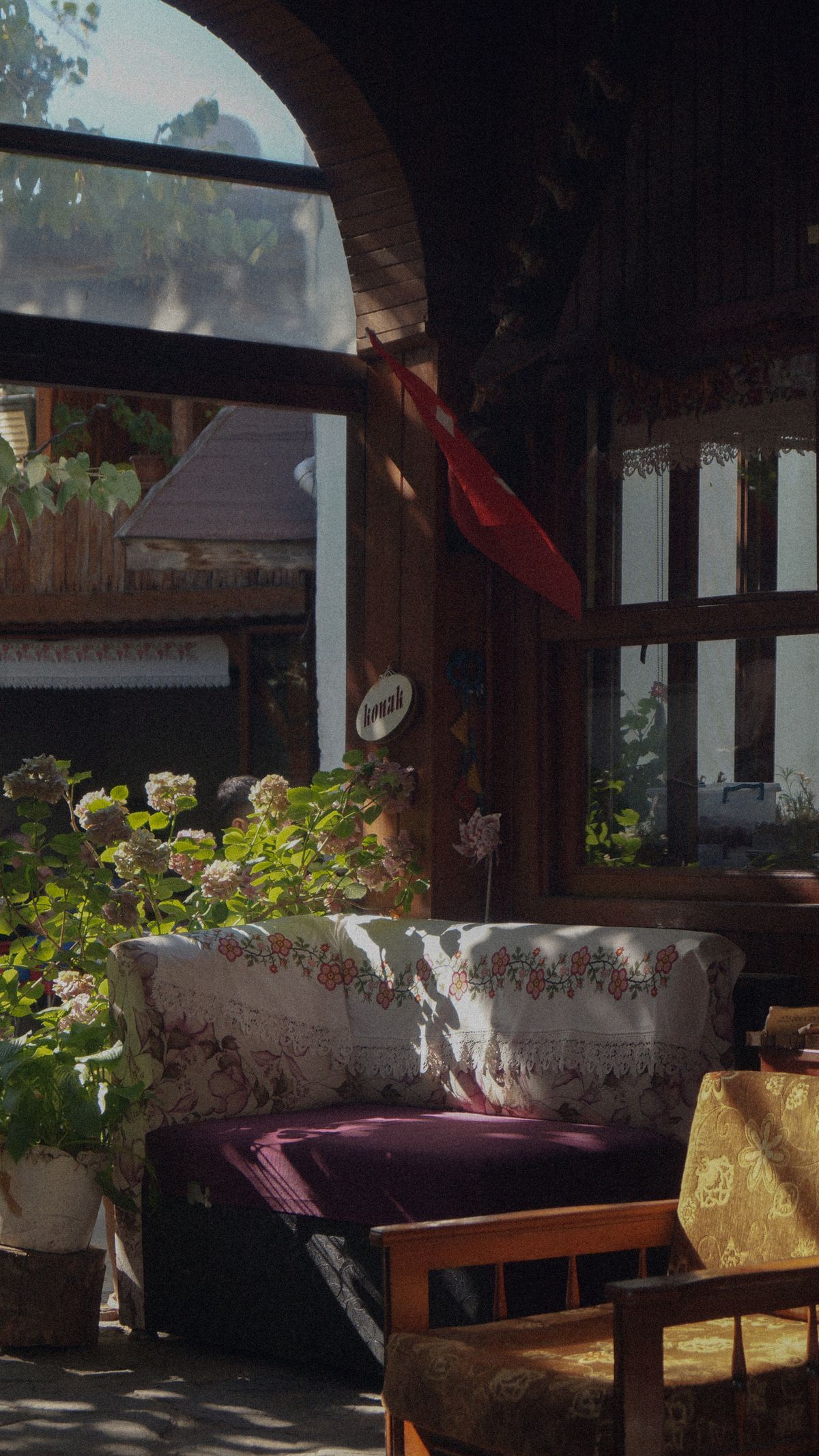 Cozy veranda with vintage furniture and floral patterns, sunlit ambiance. Stock Photo.