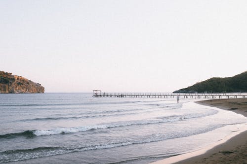 A beach with a pier and a body of water