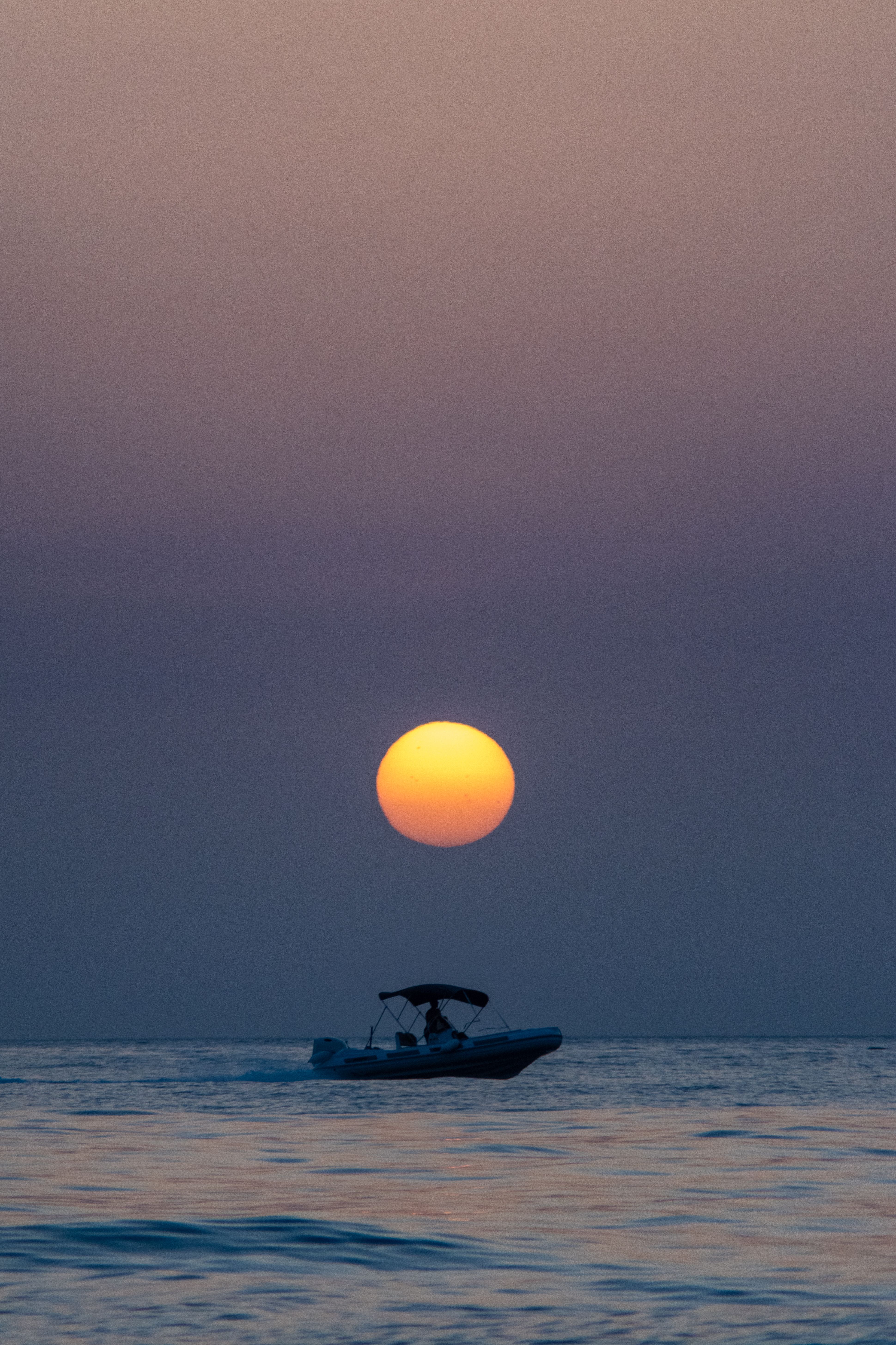 A boat cruises during a stunning sunset over the sea at Bagnara Calabra, Calabria, Italy.