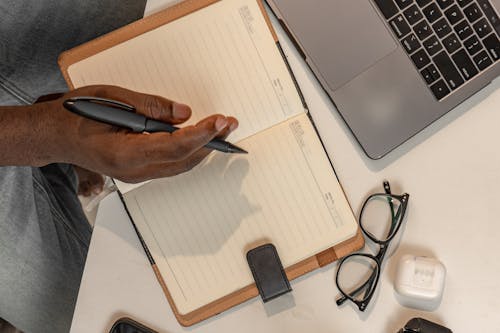 Top View of a Man Sitting at a Desk with a Laptop and a Notebook 