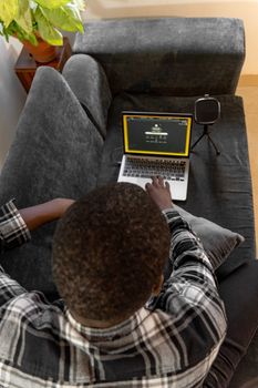 Overhead view of a man using a laptop on a cozy sofa in a home setting.