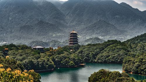 Free A pagoda rises above a dense forest with mountains in the background, creating a tranquil and picturesque scene. Stock Photo