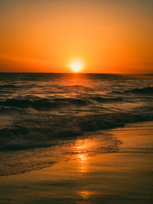Free Experience the serene beauty of a Mazatlán sunset on the beach with golden reflections and gentle waves. Stock Photo