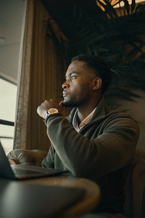 Man Sitting by Table with Laptop