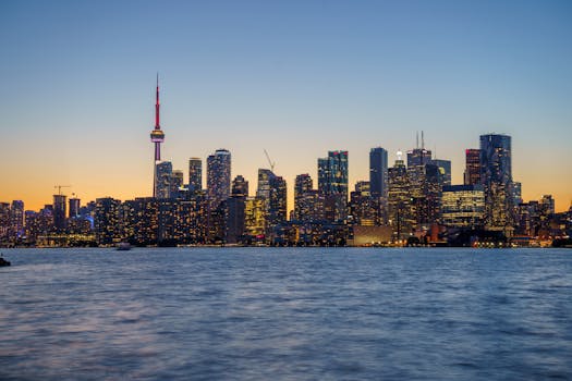 Stunning Toronto skyline with CN Tower at sunset, viewed across Lake Ontario.