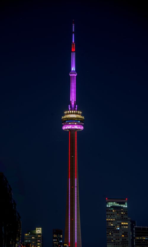 Free Stunning view of the CN Tower glowing with colorful lights against a dark night sky. Stock Photo