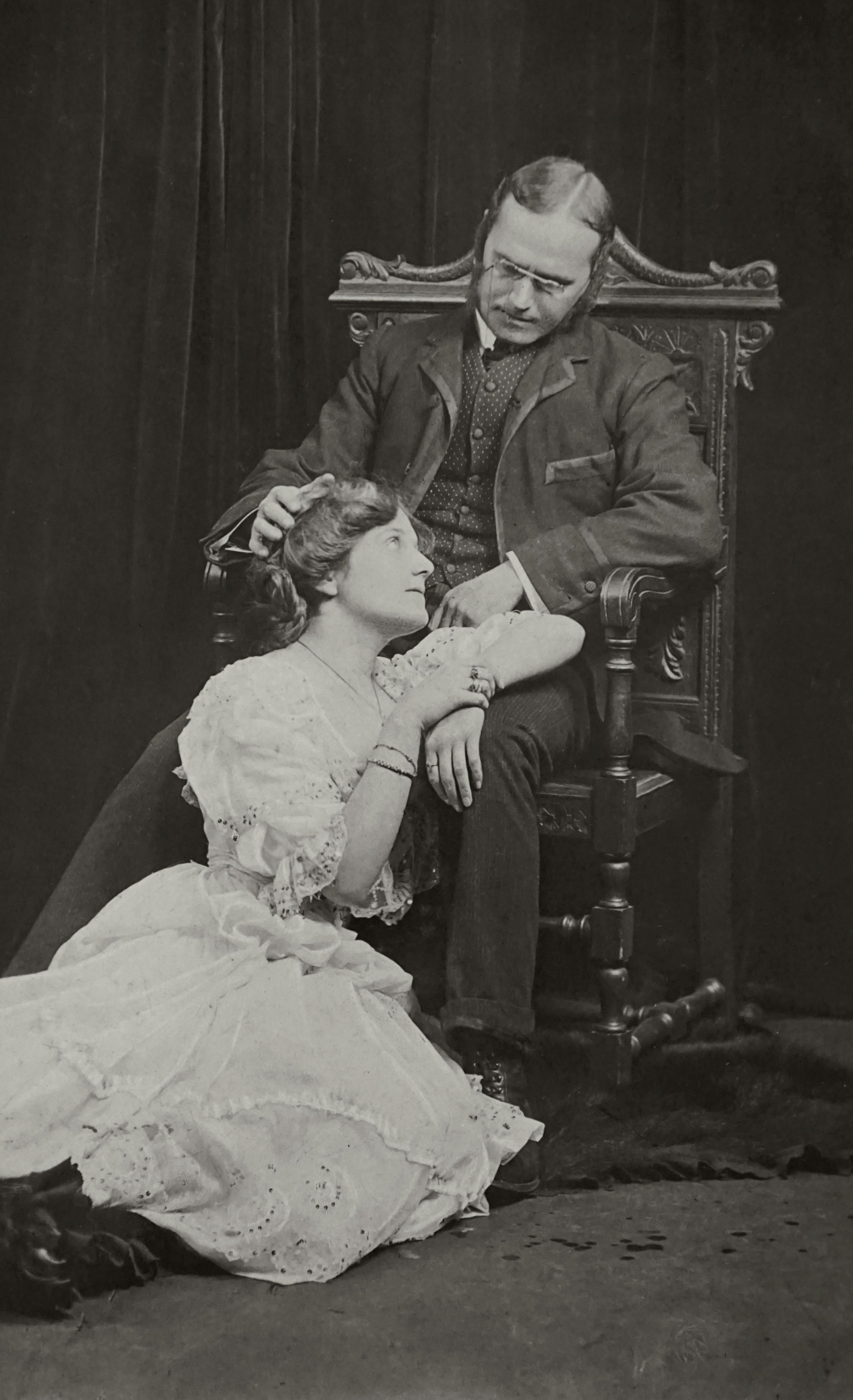 Classic vintage portrait of a father and daughter in an armchair, evoking nostalgia.