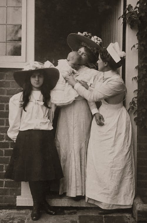 Old Photograph of Two Women, a Girl and a Baby Standing in front of a House 