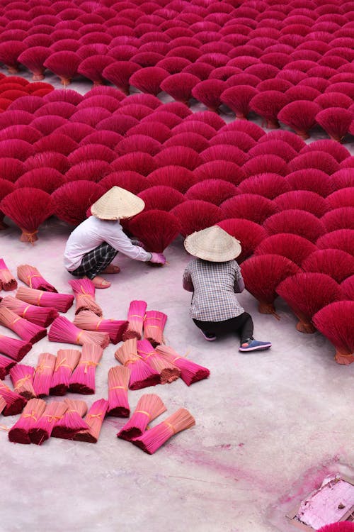 People Working with Red Incense Sticks
