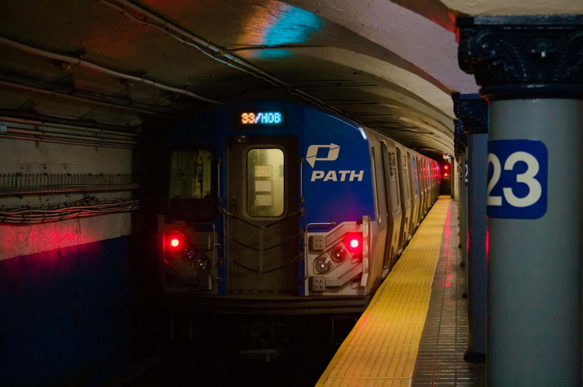 PATH train arriving at dimly lit subway platform 23, showcasing urban transit in an underground tunnel.