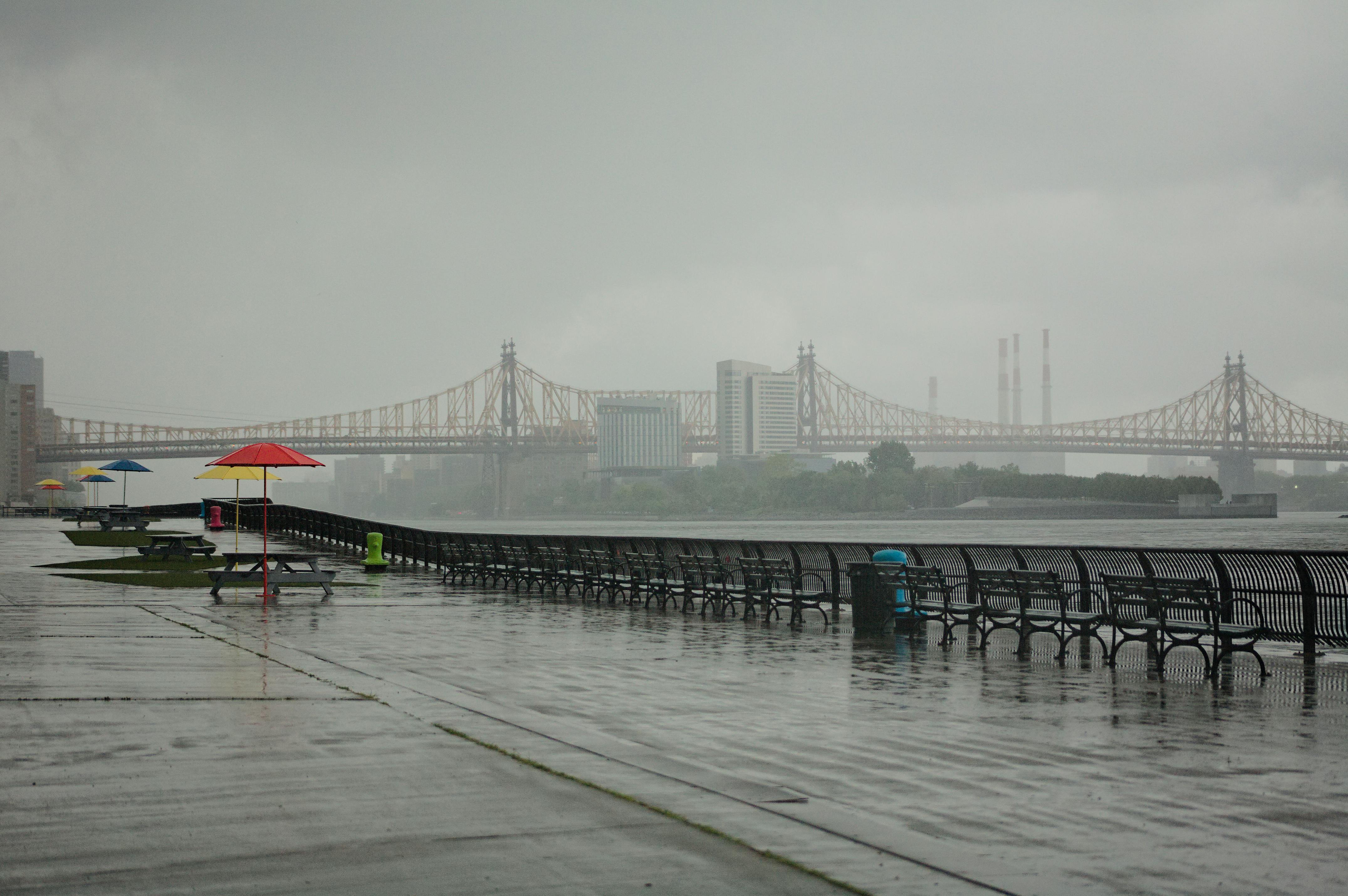 a rainy day with a bench and umbrella on the sidewalk