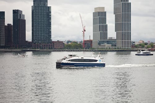 A ferry boat is traveling on the water near some tall buildings